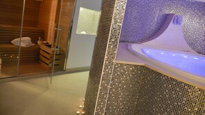 Een moderne spa met een sauna met glazen wanden, een ruime jacuzzi en houten banken.