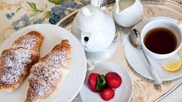 Una bandeja con pasteles, fresas, un ramillete de té y una taza de té.