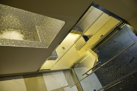 A high-angle view of a hotel corridor with patterned metal railings and a tiled floor.