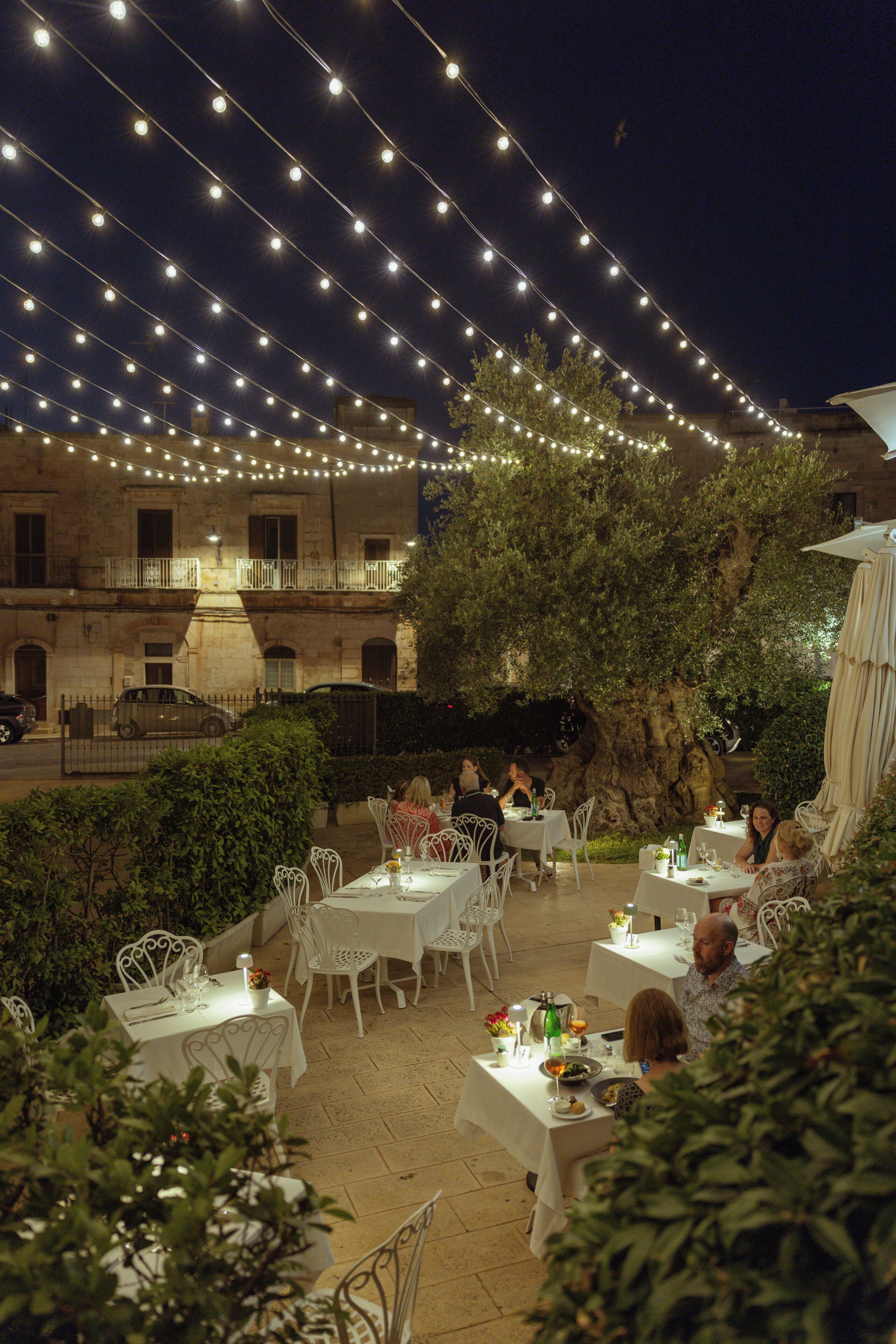 An outdoor dining area with string lights overhead and tables set for guests.