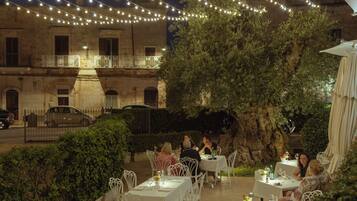 Un espacio para comer al aire libre con luces colgantes y mesas preparadas para comensales.