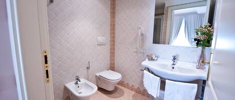 Un baño con bidé, inodoro, lavabo y espejo.