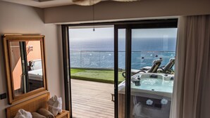 Une pièce dotée d’une grande porte-fenêtre coulissante donnant sur un balcon avec vue sur la mer.