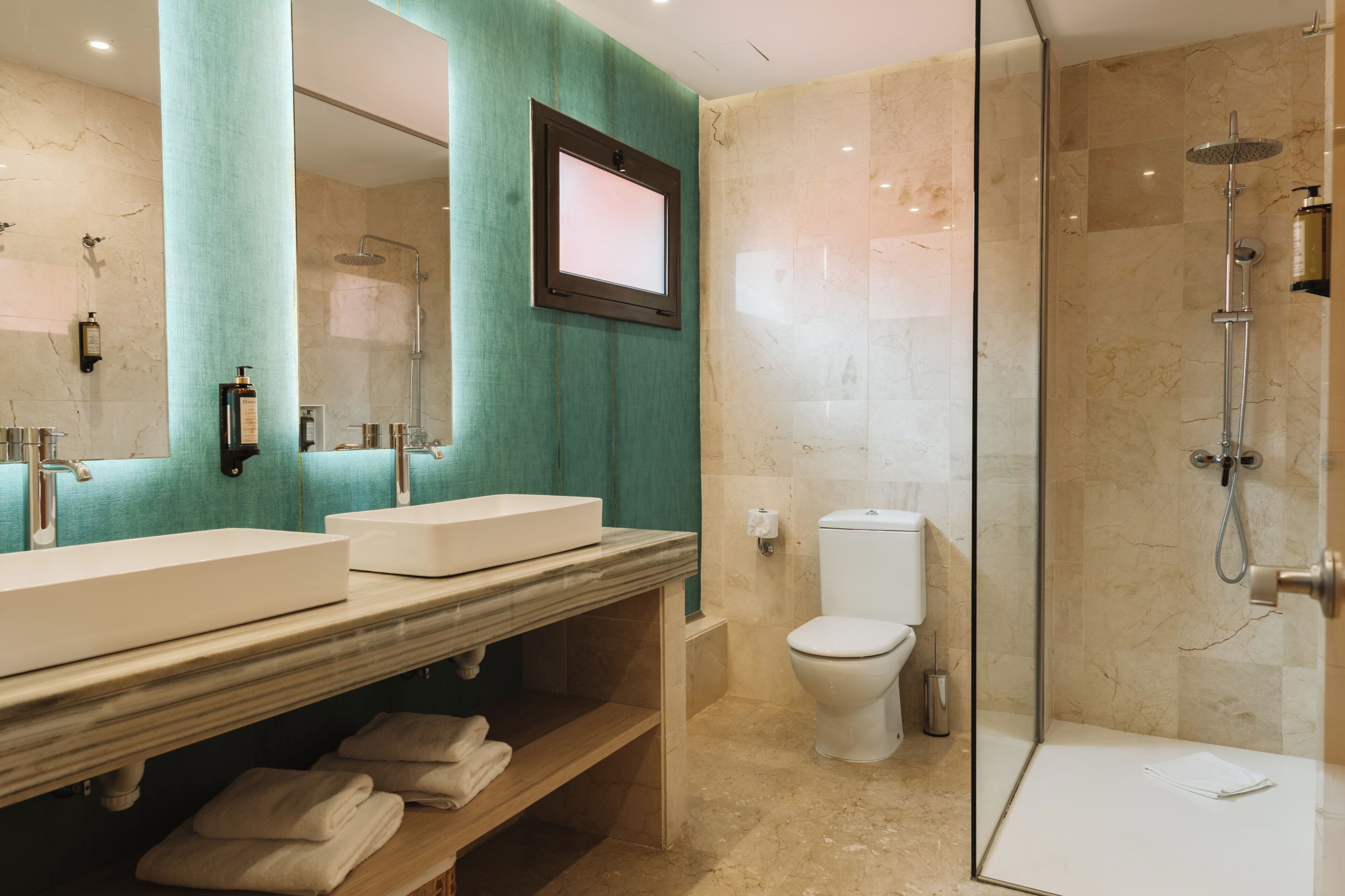 A modern bathroom with two sinks, a toilet, and a glass-enclosed shower.