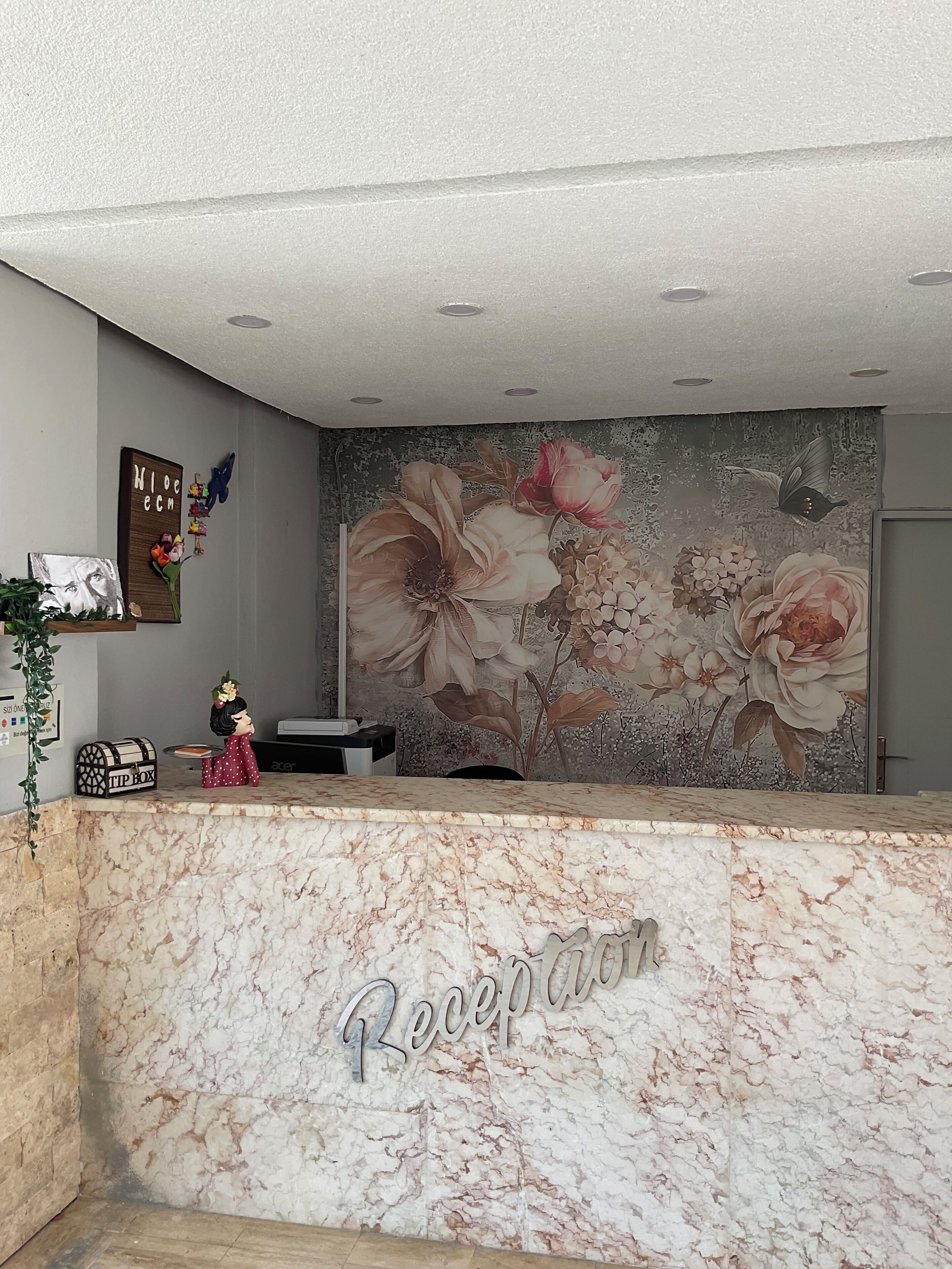 A reception desk with a marble top and a floral mural in the background.