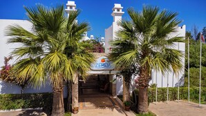 A hotel entrance with palm trees, a sign reading "ZEMDA HOTEL GUMOSLUK", and a clear blue sky. - Ladonia Hotels Zemda Gümüşlük (Bodrum)