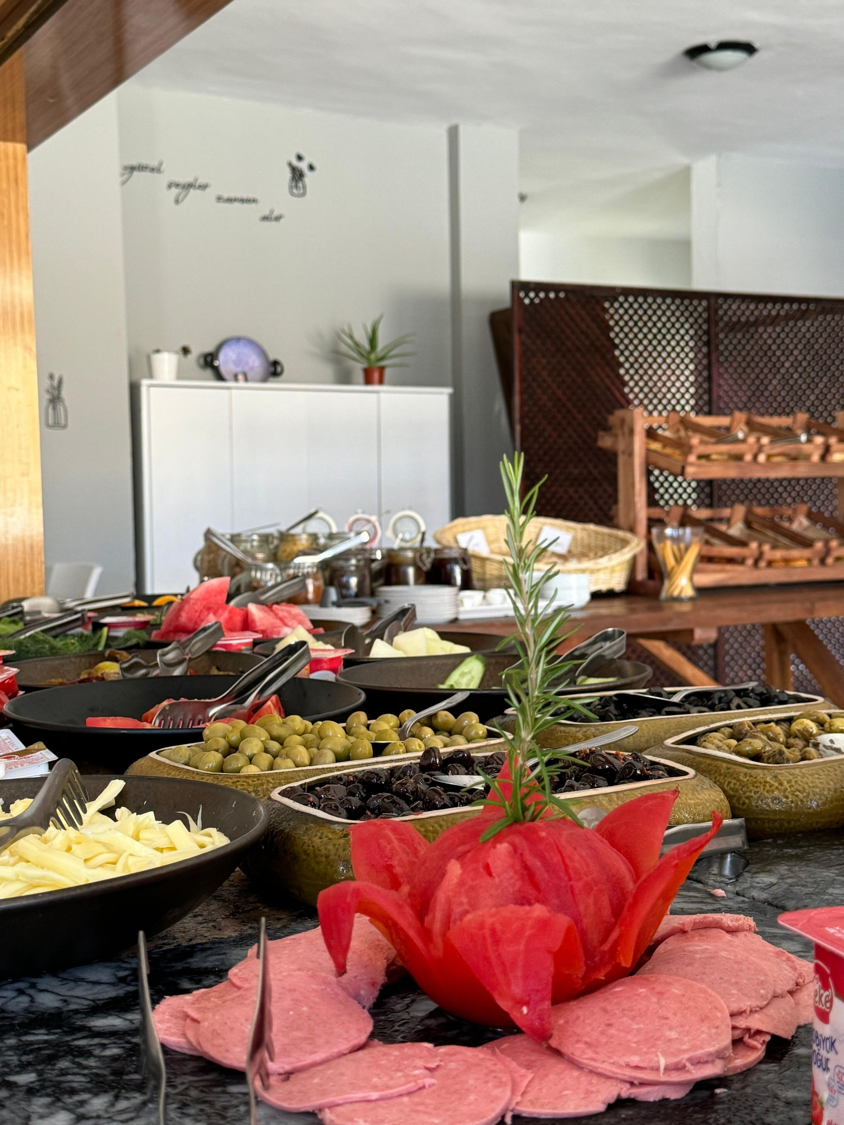 A buffet with various food items including olives, sliced meats, and vegetables.