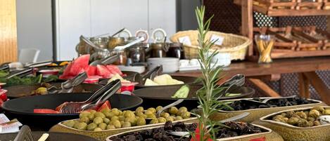 A buffet with various food items including olives, sliced meats, and vegetables.