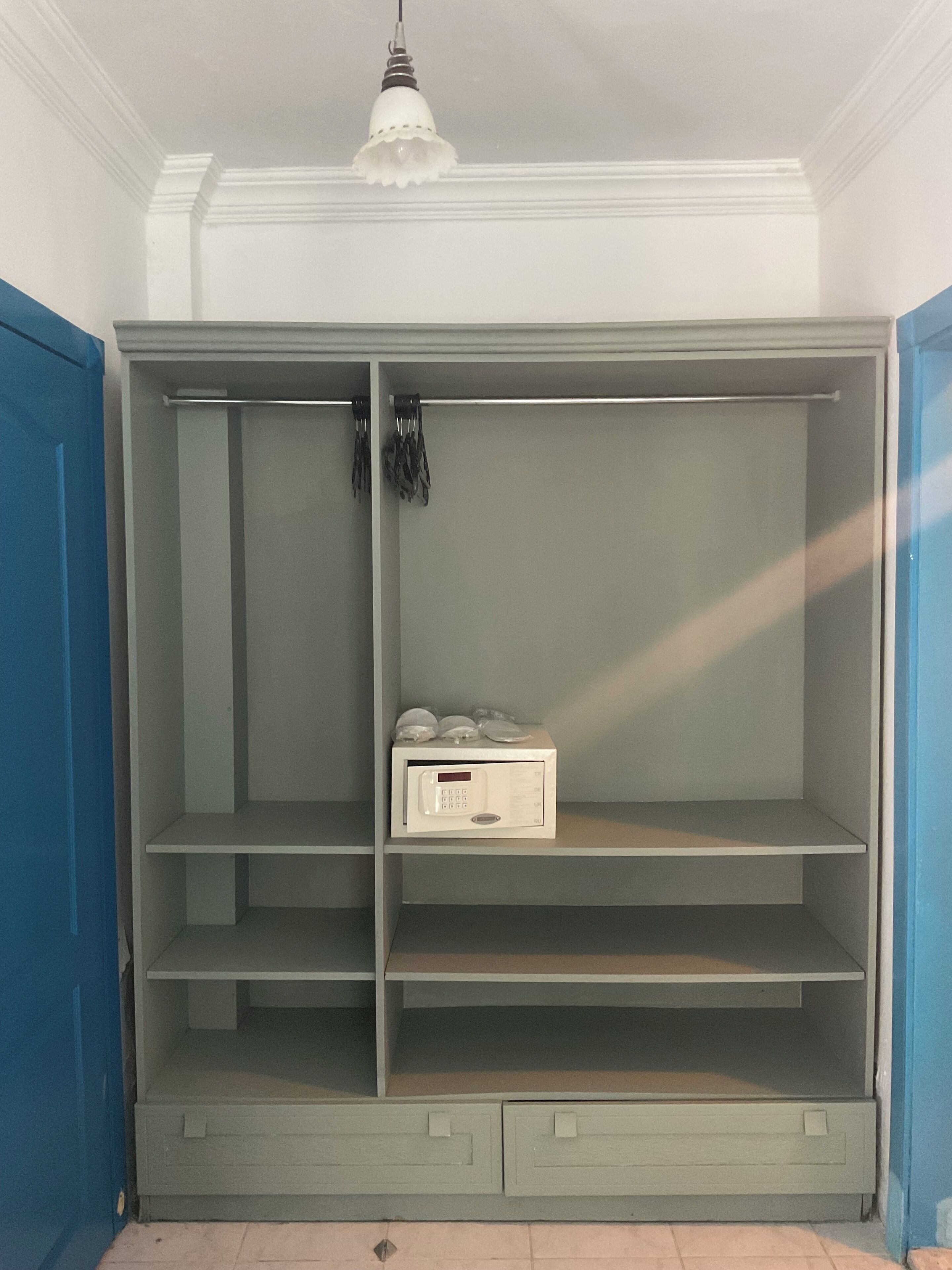 A walk-in closet with a white ceiling, a hanging light fixture, and a microwave on the lower shelf.