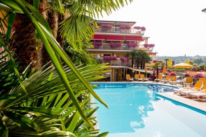 Una piscina al aire libre, sombrillas, sillones reclinables de piscina