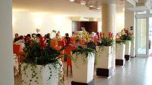 A spacious lobby with modern decor, featuring potted plants and a seating area for guests. - Hotel Capri (Bardolino)