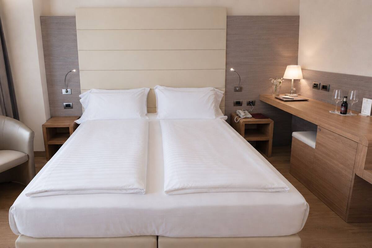 A hotel room with a large bed, a chair, a desk, and a nightstand.
