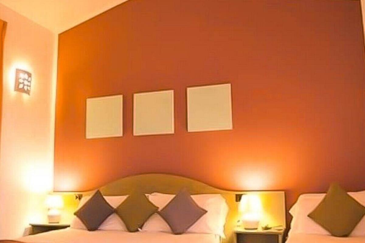 A hotel room with two beds, a large window, and a wall-mounted light fixture.