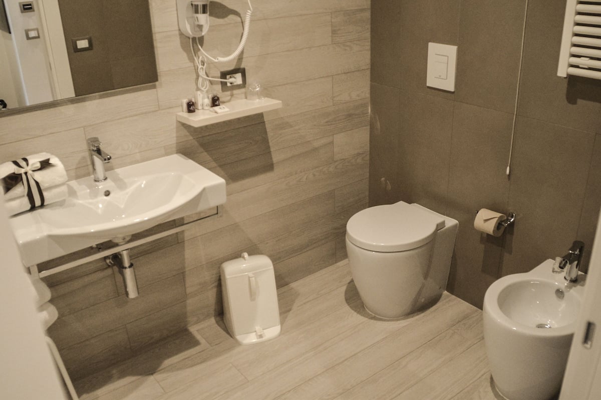 A modern bathroom with a sink, toilet, bidet, and mirror.