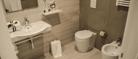 A modern bathroom with a sink, toilet, bidet, and mirror.