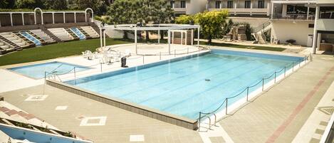 A large outdoor swimming pool with a seating area and a covered section.