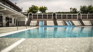 Une piscine avec des marches permettant d’y accéder, entourée d’une clôture et bordée d’un bâtiment doté d’un escalier.
