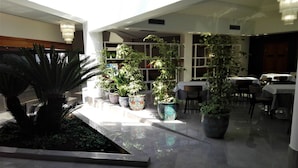 Un vaste espace intérieur doté d’un plancher ciré, de plusieurs plantes en pot et de tables disposées pour les repas.