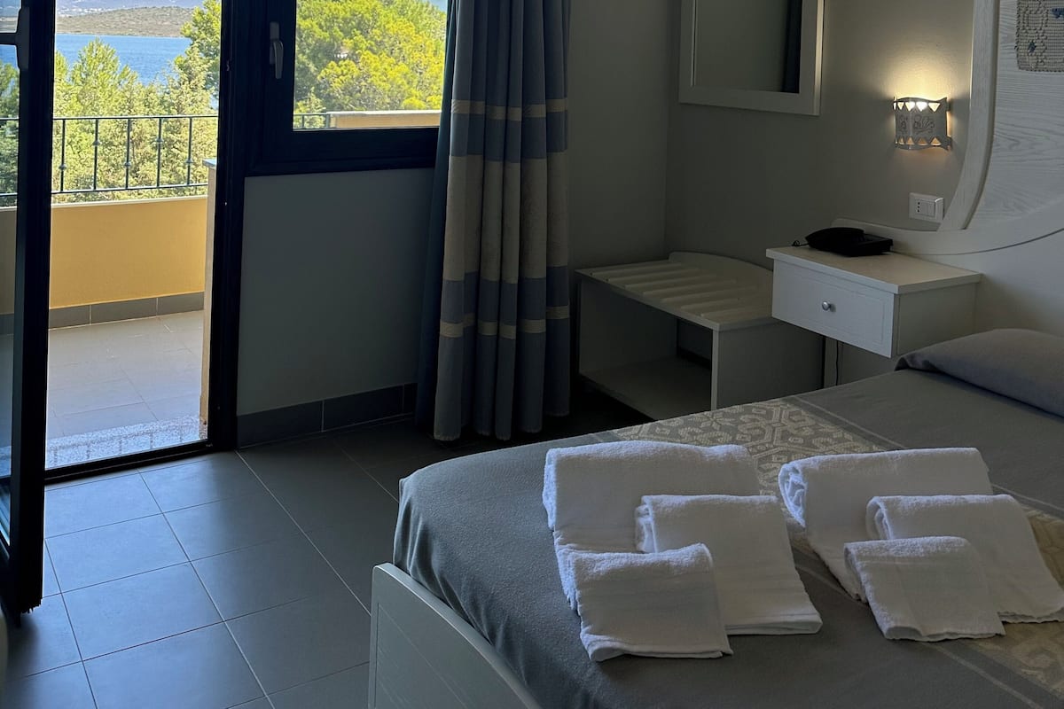 Une chambre d’hôtel comprenant un lit, une table de chevet, une commode, un miroir et une vue sur l’extérieur.