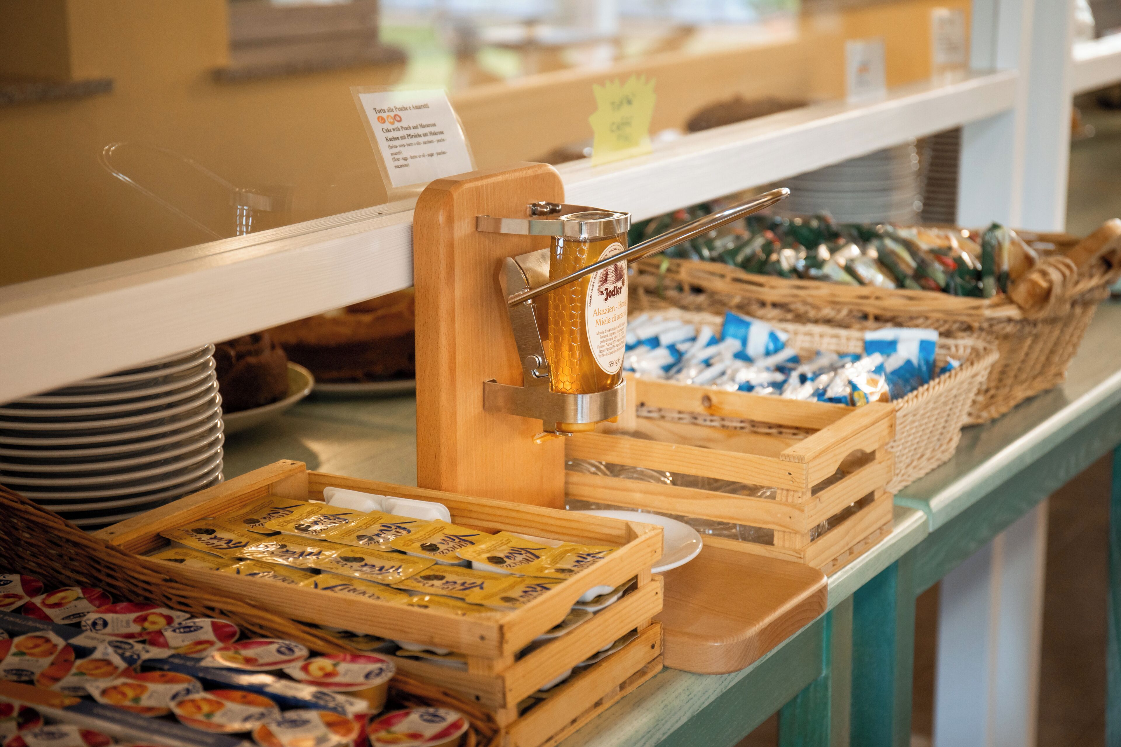 A buffet setup with various food items and a honey dispenser.