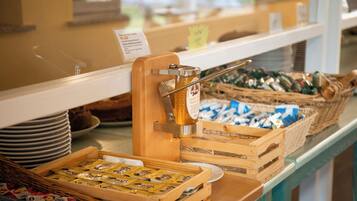 A buffet setup with various food items and a honey dispenser.