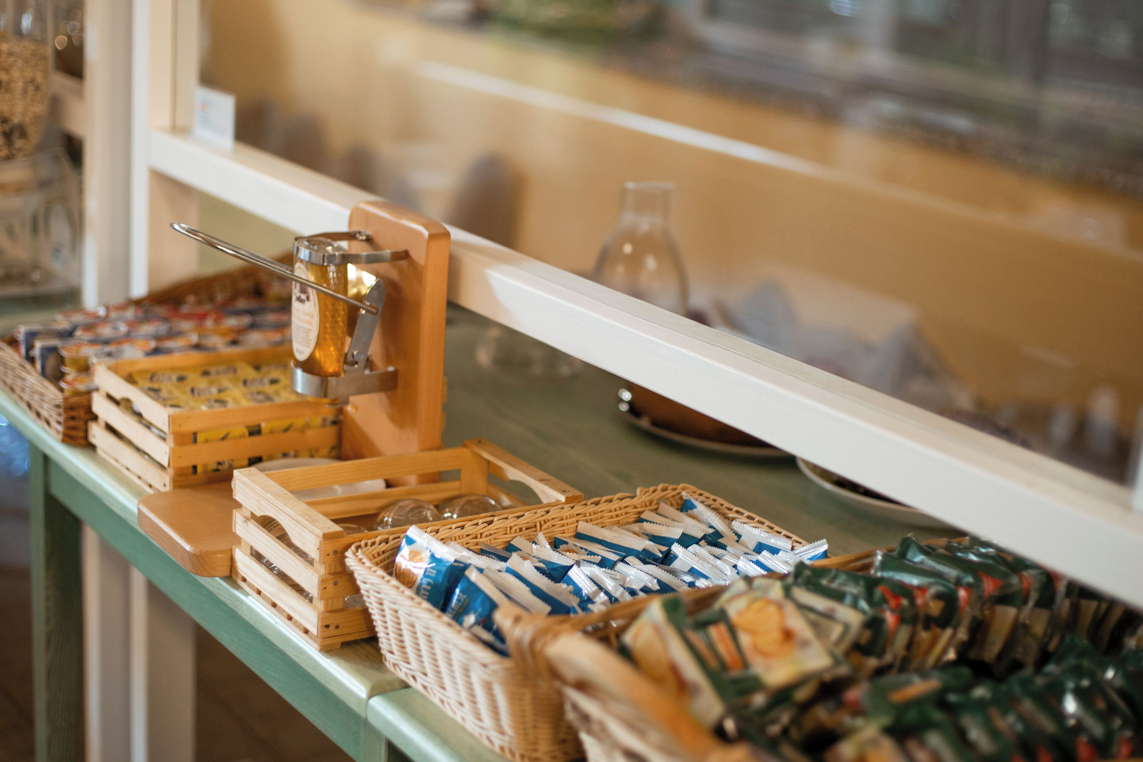 A buffet setup with various food items and a honey dipper on a table.