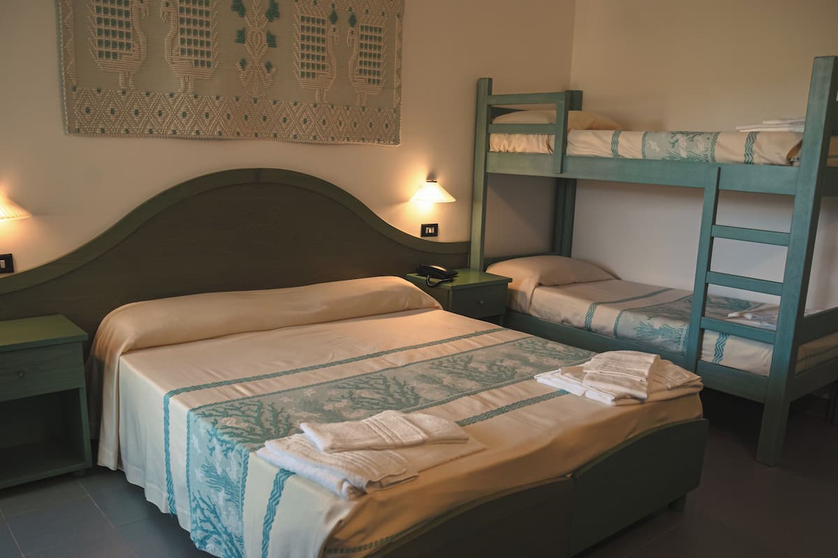 Une chambre avec deux lits superposés, une table de chevet, une lampe et une décoration murale.
