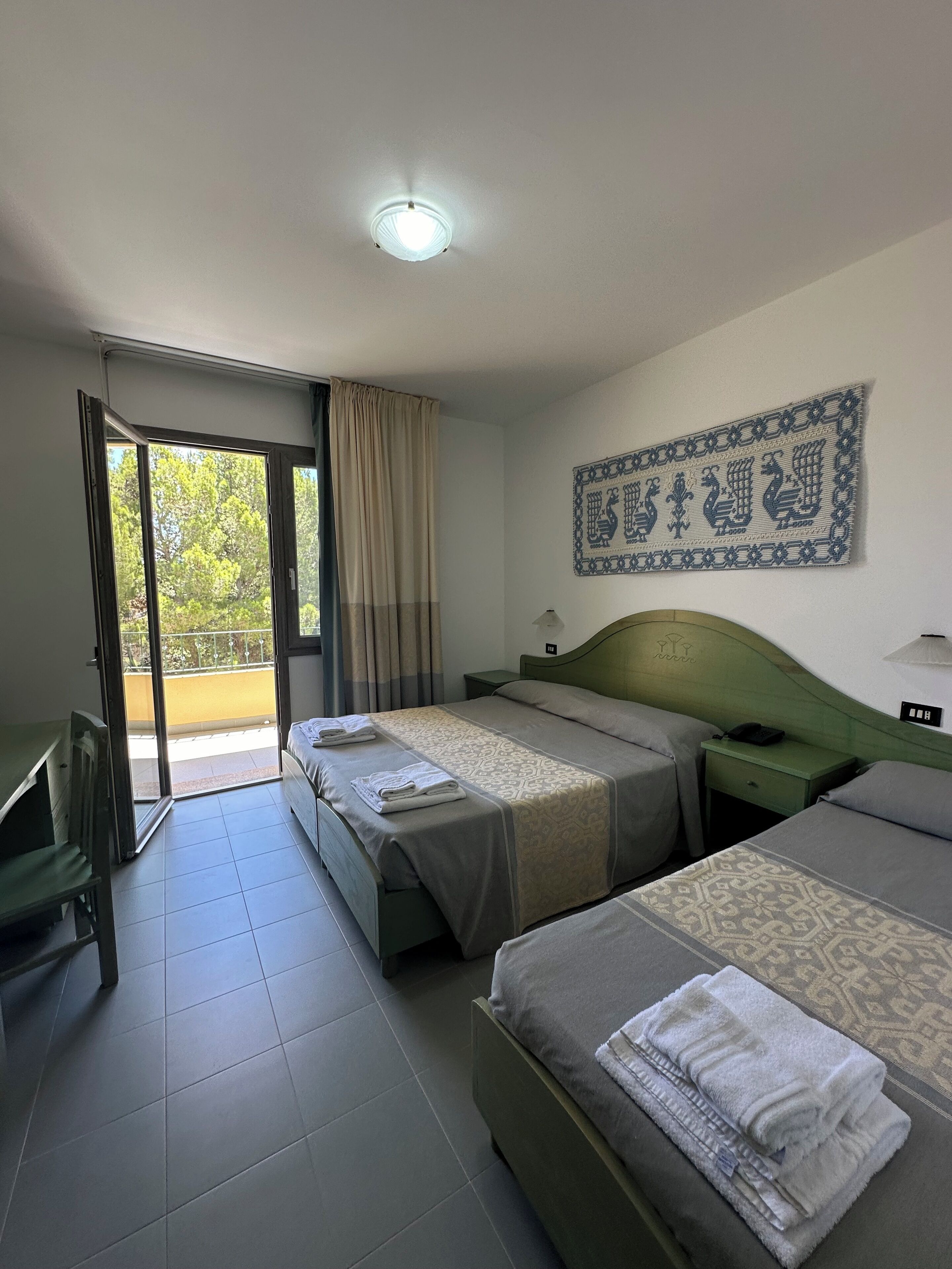 Een hotelkamer met twee bedden, een bureau en een balkon.