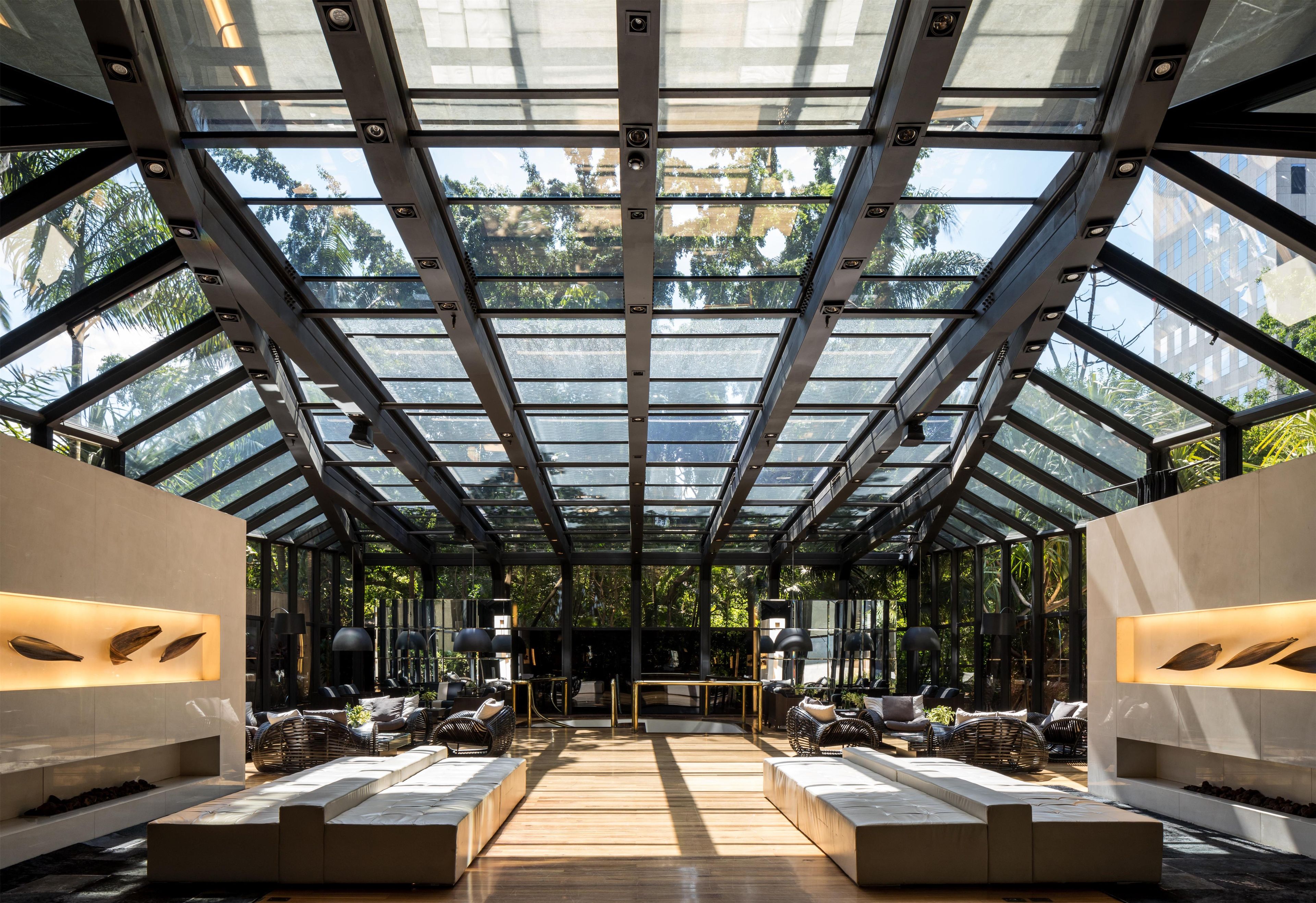 Ein modernes Interieur mit Glasdecke, Sitzbereichen und einem zentralen Tisch.