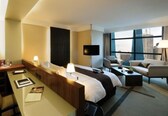 A hotel room with a bed, a desk, a chair, a TV, and a sofa.