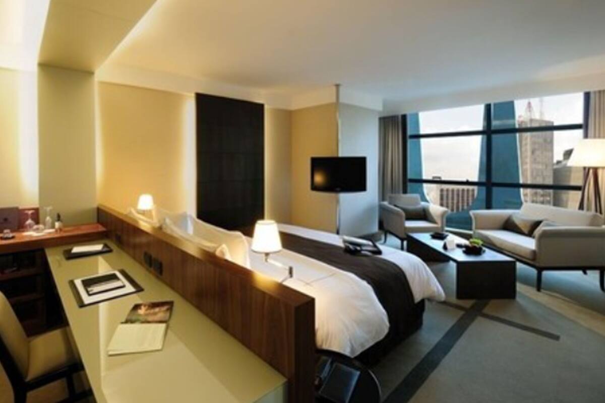 A hotel room with a bed, a desk, a chair, a TV, and a sofa.