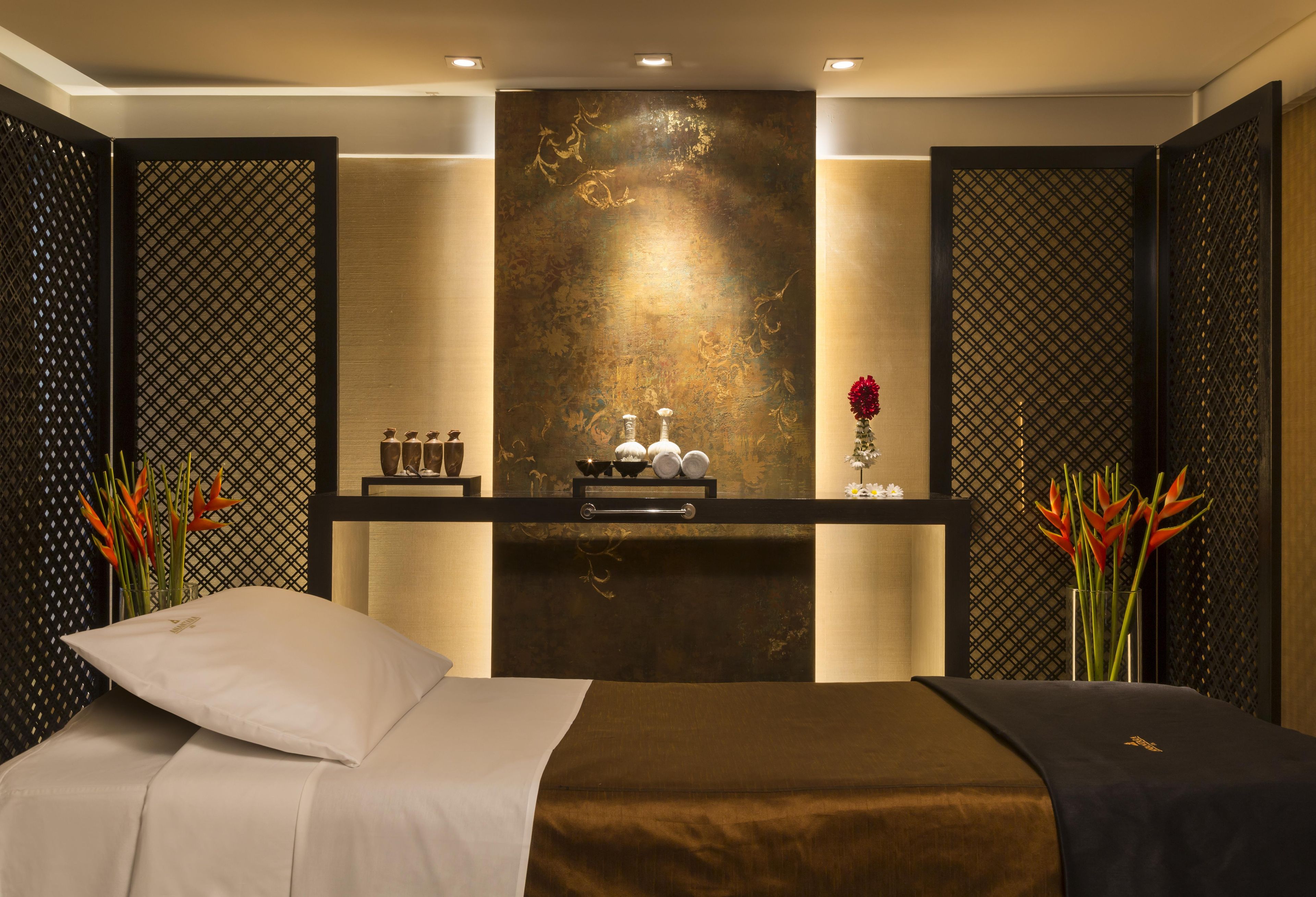 Una habitación de hotel con una cama, un tocador con artículos de aseo y plantas decorativas.