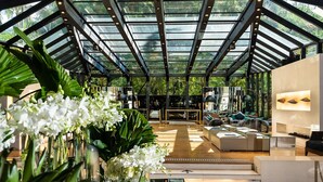Un interior espacioso y moderno con techo de vidrio, un área de estar central y abundante vegetación.
