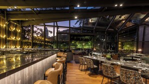 Un restaurante moderno con barra, suelo de madera y sillas estampadas.