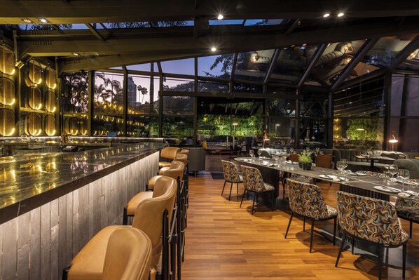 Un restaurante moderno con barra, suelo de madera y sillas estampadas.
