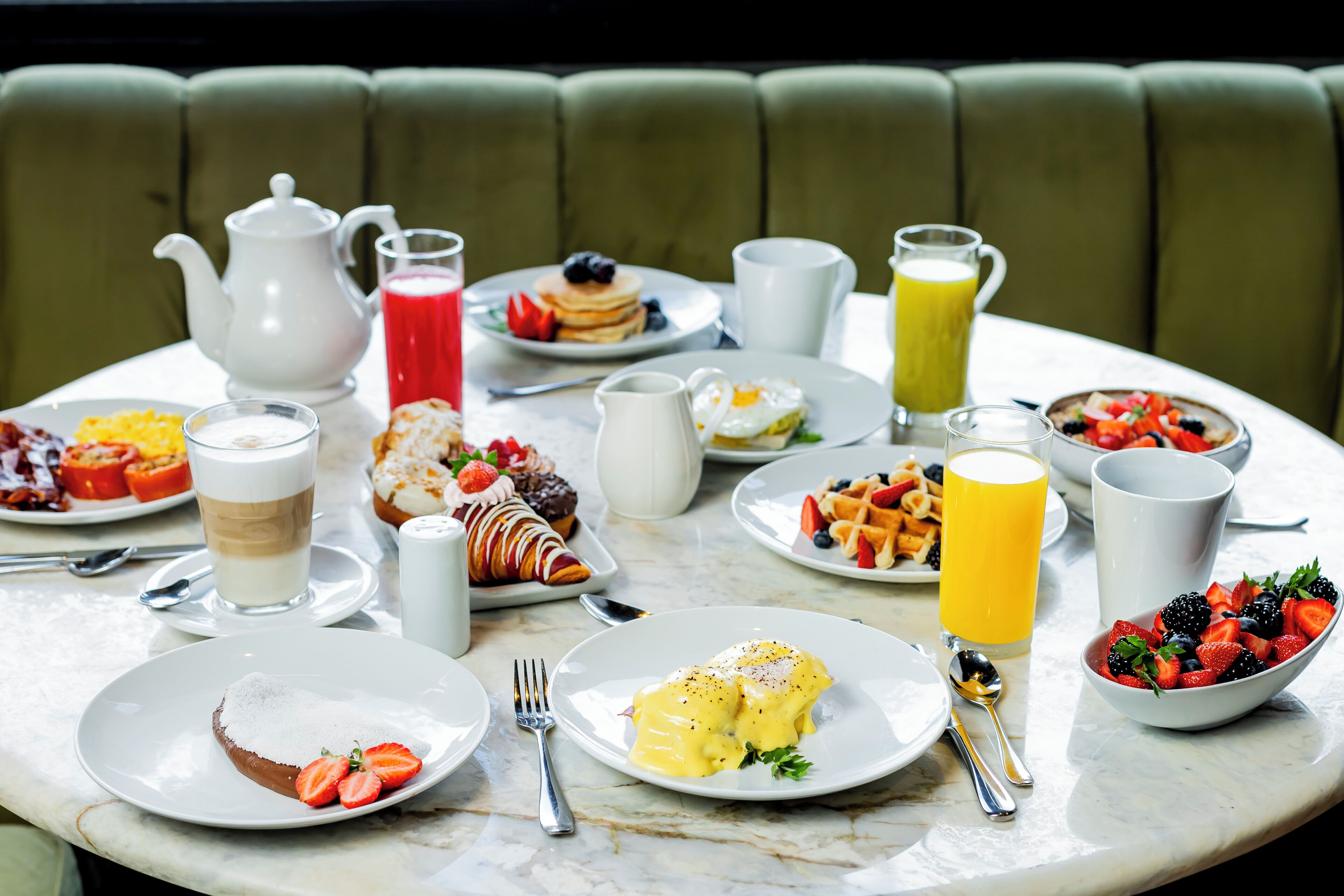 A breakfast table with various dishes and drinks.