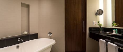 Un baño moderno con una bañera independiente, una puerta de madera, un mostrador negro con un lavabo y un espejo.
