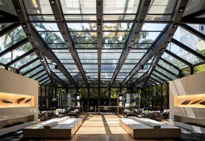 Un intérieur moderne avec un plafond en verre, des espaces de détente et une table centrale.