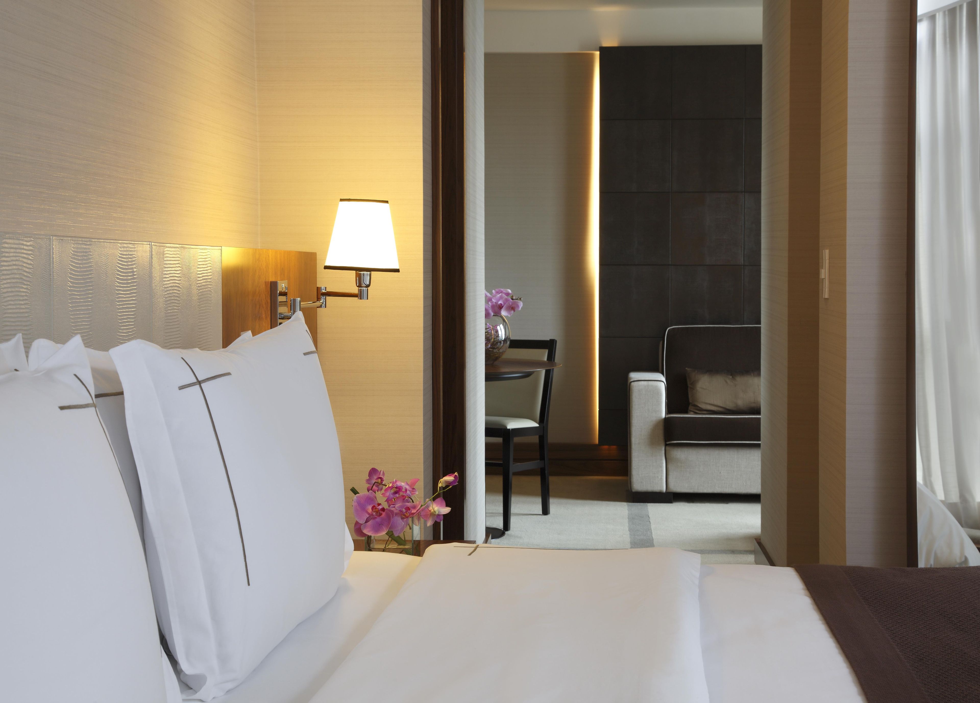 Una habitación de hotel con cama, escritorio, silla y lámpara.