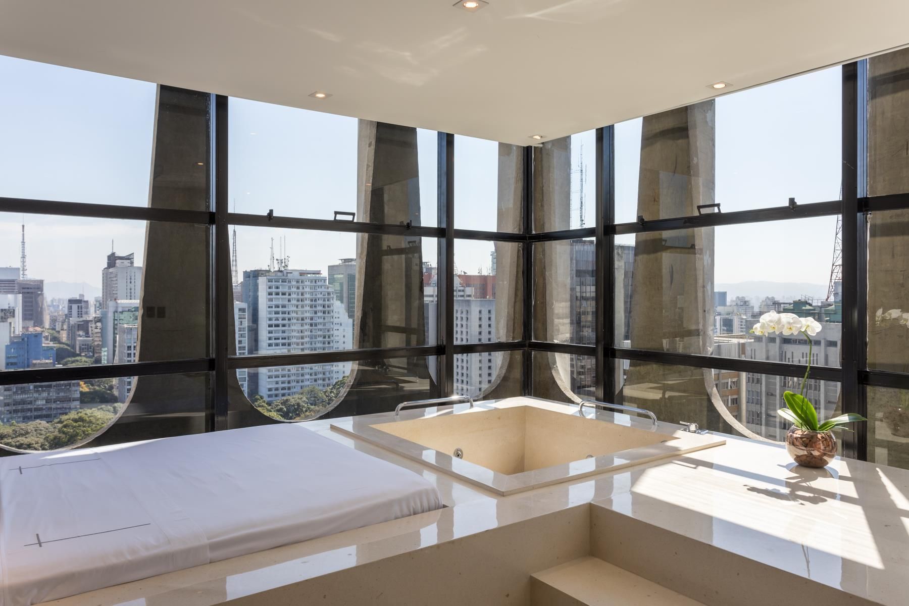 Een moderne badkamer met een bad, een wastafel en een groot raam met uitzicht op de stad.