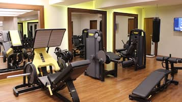 A gym with various exercise equipment, including weight machines and a bench.