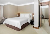 A hotel room with a large bed, a bedside table, a lamp, a chair, and a door.