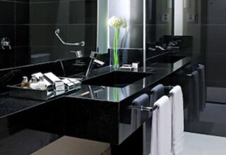 A modern bathroom with a large mirror, a black countertop, and a white towel hanging on the wall.