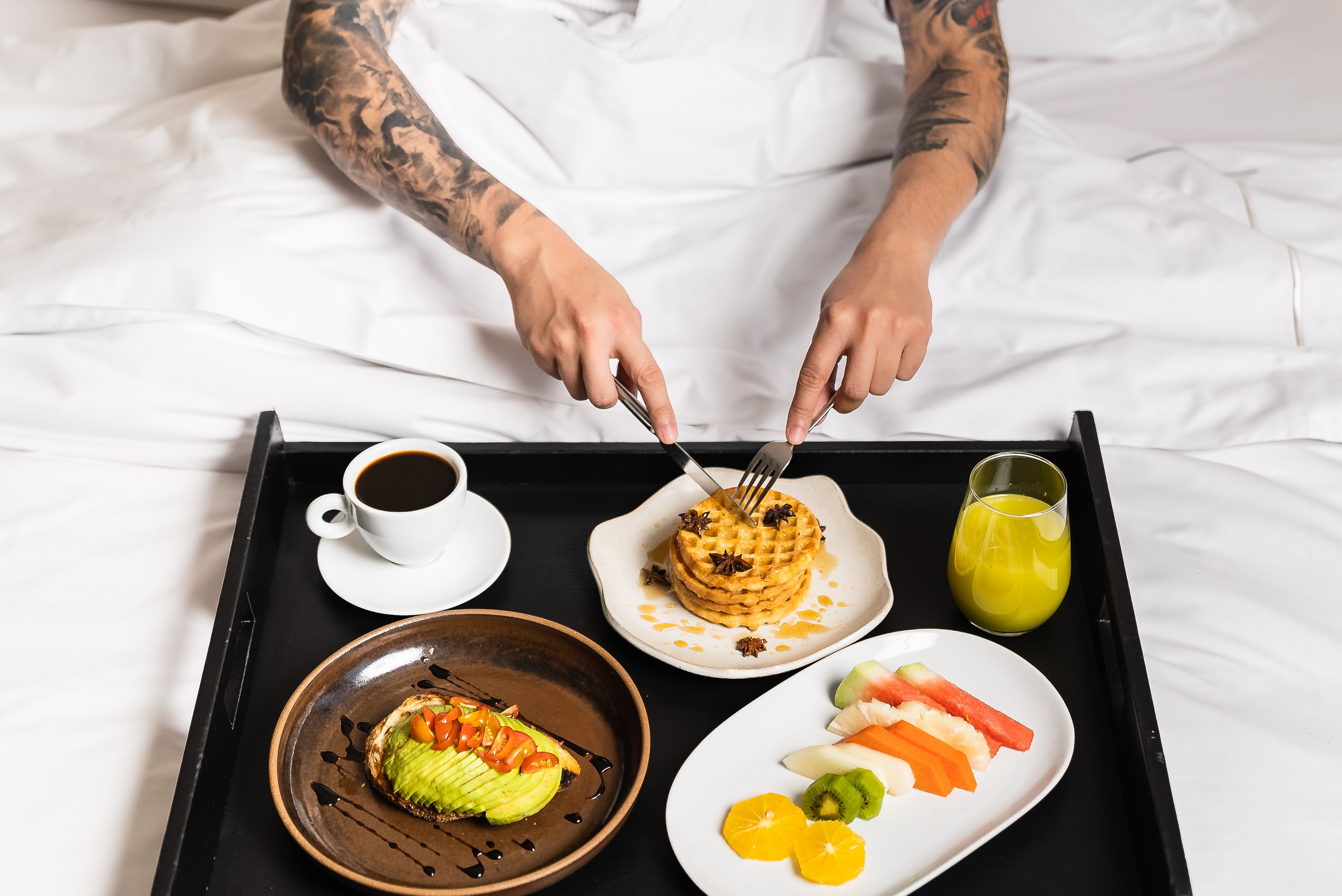 A tray with breakfast items including pancakes, coffee, juice, and fruit.