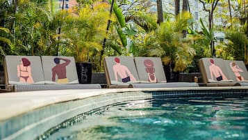 Zona junto a la piscina con sillas de descanso y una piscina con baldosas.