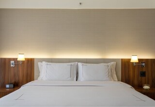 A hotel room with a large bed, two bedside tables, and wall-mounted lamps.