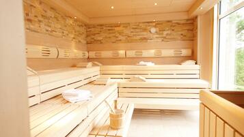 Eine Sauna mit Holzbänken, einer Steinwand und einem Fenster für natürliches Licht.
