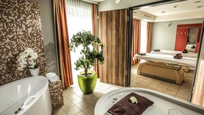 Une salle de bain moderne avec une baignoire, un grand miroir, un lavabo et une plante en pot.