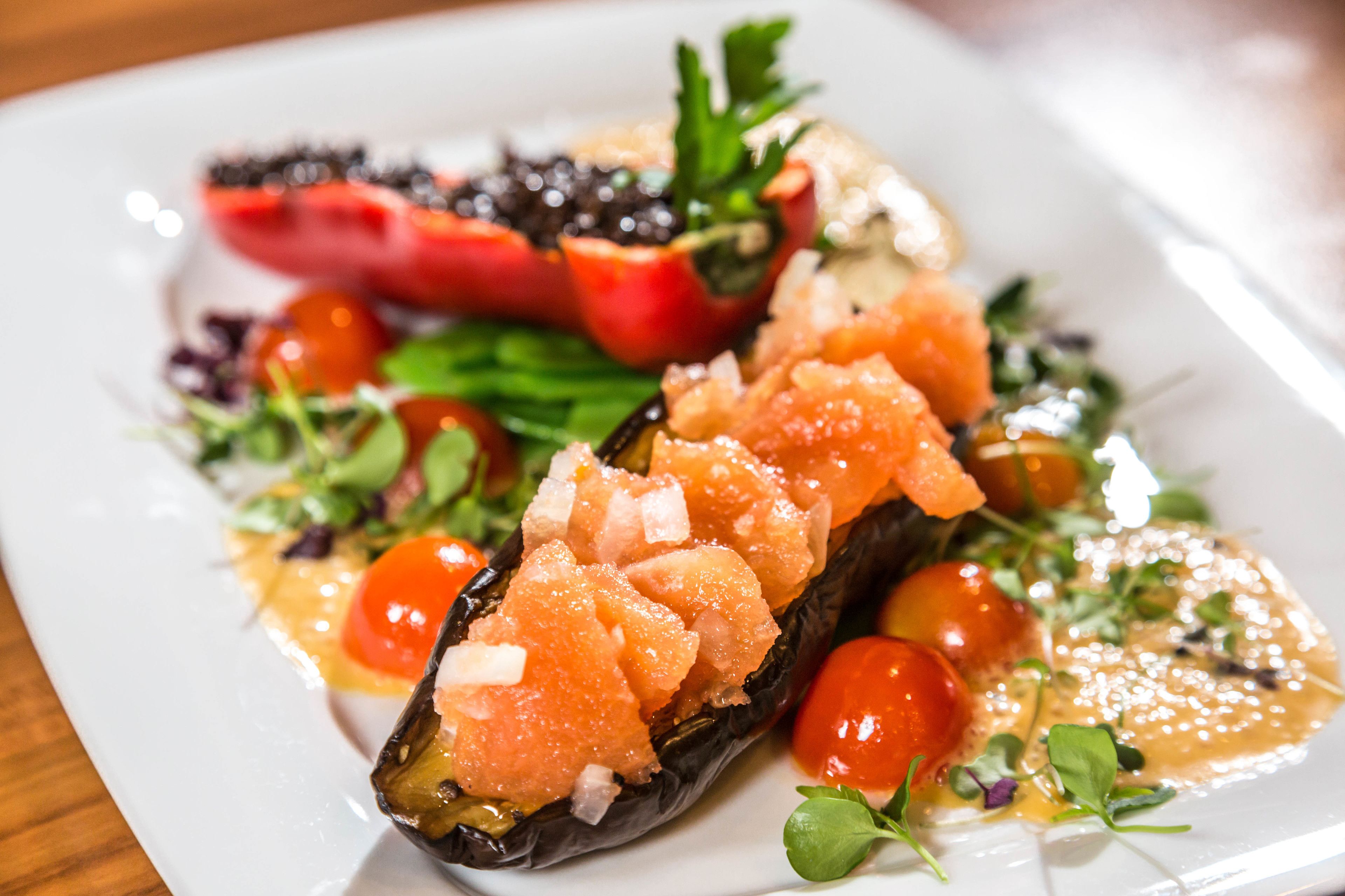 A plate of food with salmon, cherry tomatoes, and greens.