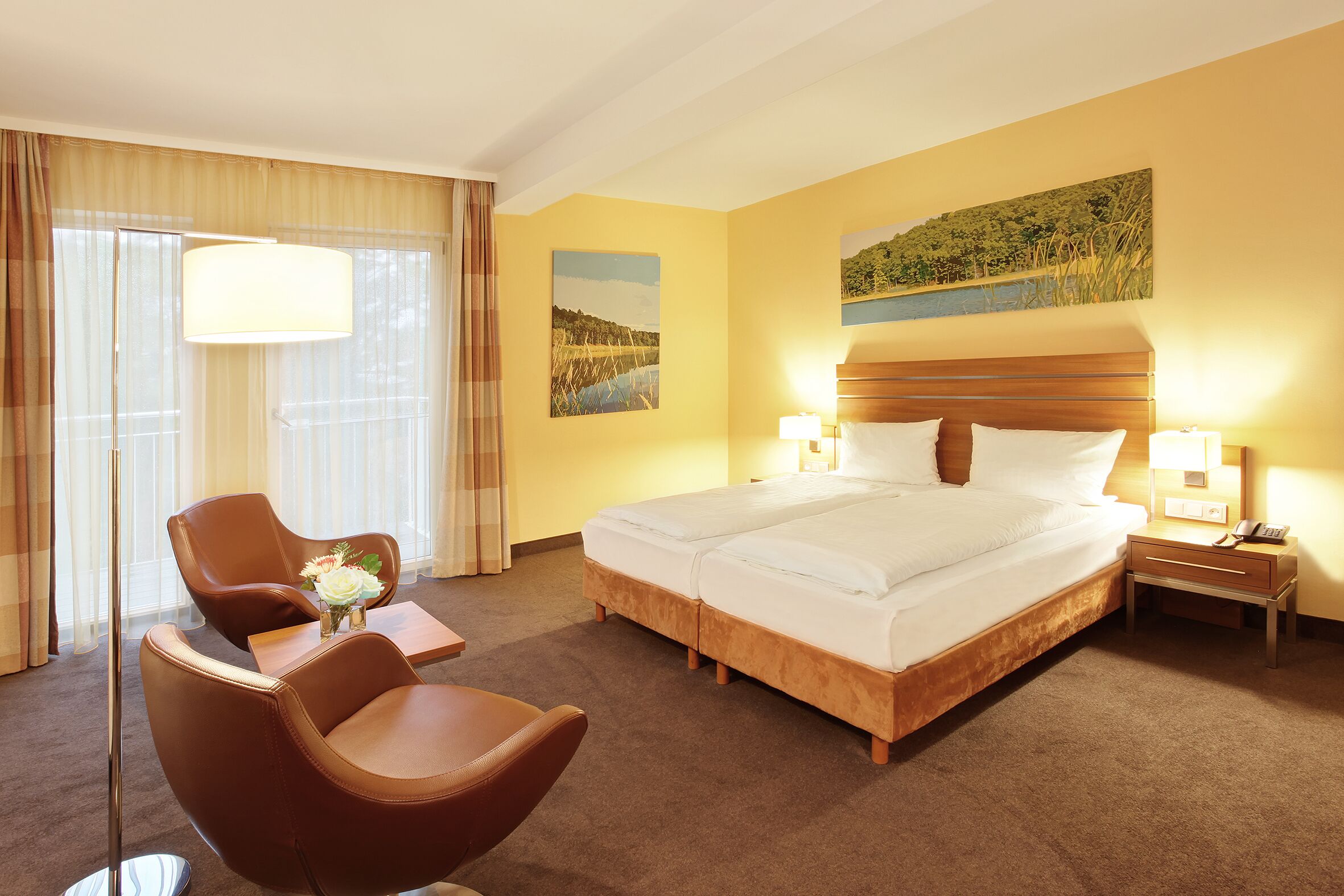 A hotel room with a large bed, a chair, a desk, and a lamp.